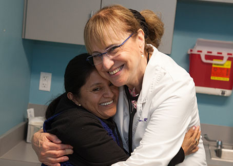Vicky hugging a female patient, highlighting the warm and welcoming medical home BVMI provides for patients.