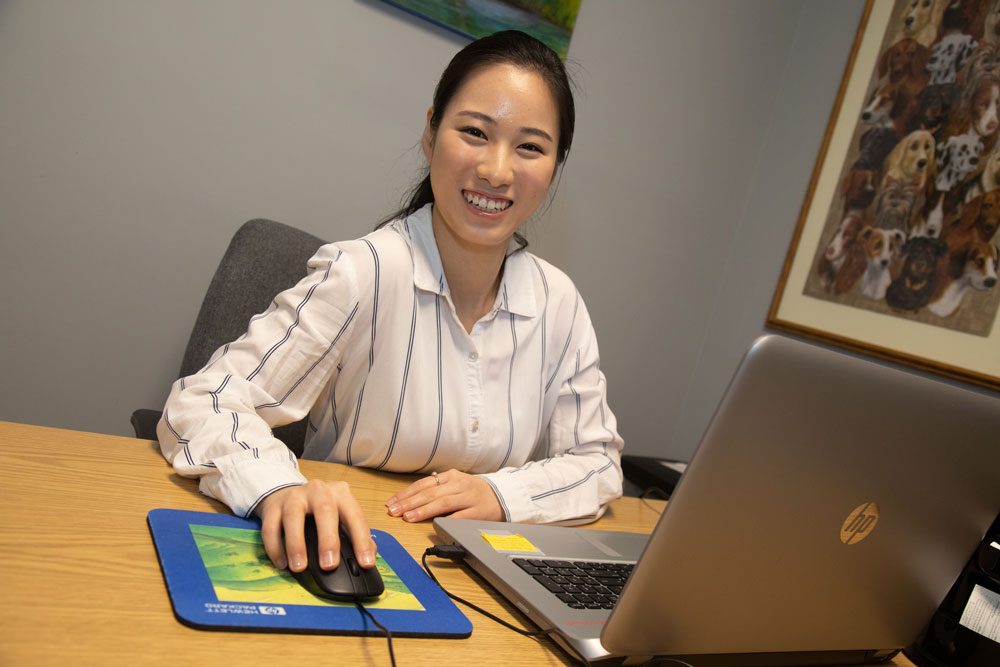 Korean volunteer seated behind the desk in the patient eligibilty office.