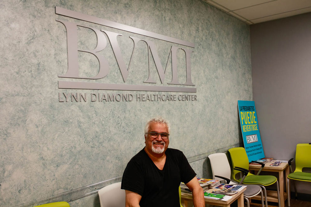 Male patient in waiting room with the BVMI name in the background behind him.
