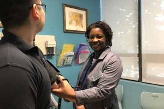 BVMI Staff Nurse Karla taking the blood pressure of a patient in one of the healthcare center exam rooms.